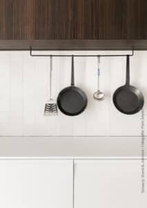 Moderne witte keuken met bovenkasten in een warme houtlook, de LR29 Riga van Cleaf, welke een driedimensionaal lijnenspel combineert met warme houtdecors