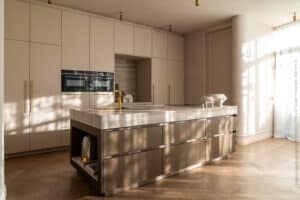 Moderne keuken, gerealiseerd in de FA84 Reflex van Cleaf, met warme bronzen invloeden, inclusief ruim kookeiland en gouden details