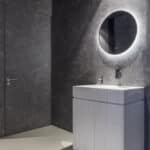 Toilet in de showroom van DecoLegno waarbij de muren zijn uitgevoerd in de FC19 Talco van Cleaf, een donkergrijze marmerlook met ultra matte finish, en het wastafelmeubel in de DM5015 Luna van Durasein, met een vloeiend lijnenspel in een serene, witte kleurmelange