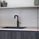 Een keuken met kasten is uitgevoerd in decoratief plaatmateriaal met het effect van verbrand hout, de S171 Bruciato van Cleaf. Het werkblad en de spatwand geven de beleving van natuursteen in decoratief plaatmateriaal FC36 Concreta van Cleaf.