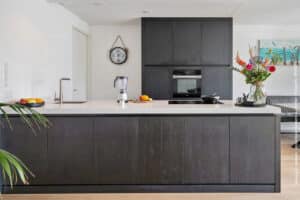 U129 Sherwood keuken met wit werkblad eiland en hoge kastenwand in decoratief plaatmateriaal zwart eiken structuur rustiek