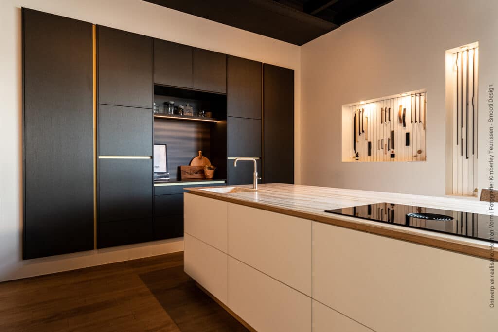 Wandkast in een keuken uitgevoerd in donkergrijs decoratief plaatmateriaal met een gemêleerd decor met de structuur van luxe zijdedraad, de FB08 Reflex van Cleaf. De fronten van het kookeiland zijn uitgevoerd in mat wit plaatmateriaal HM00 Piombo van Cleaf en het werkblad in solid surface decor Weathered Wood van Durasein.