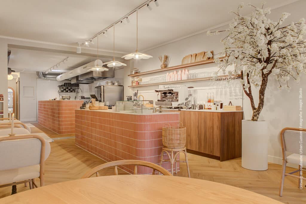 Een lunchroom met achter de balie lage wandkasten uitgevoerd in decoratief plaatmateriaal met de uitstraling van notenhout, de LS40 Poro Noce van Cleaf.