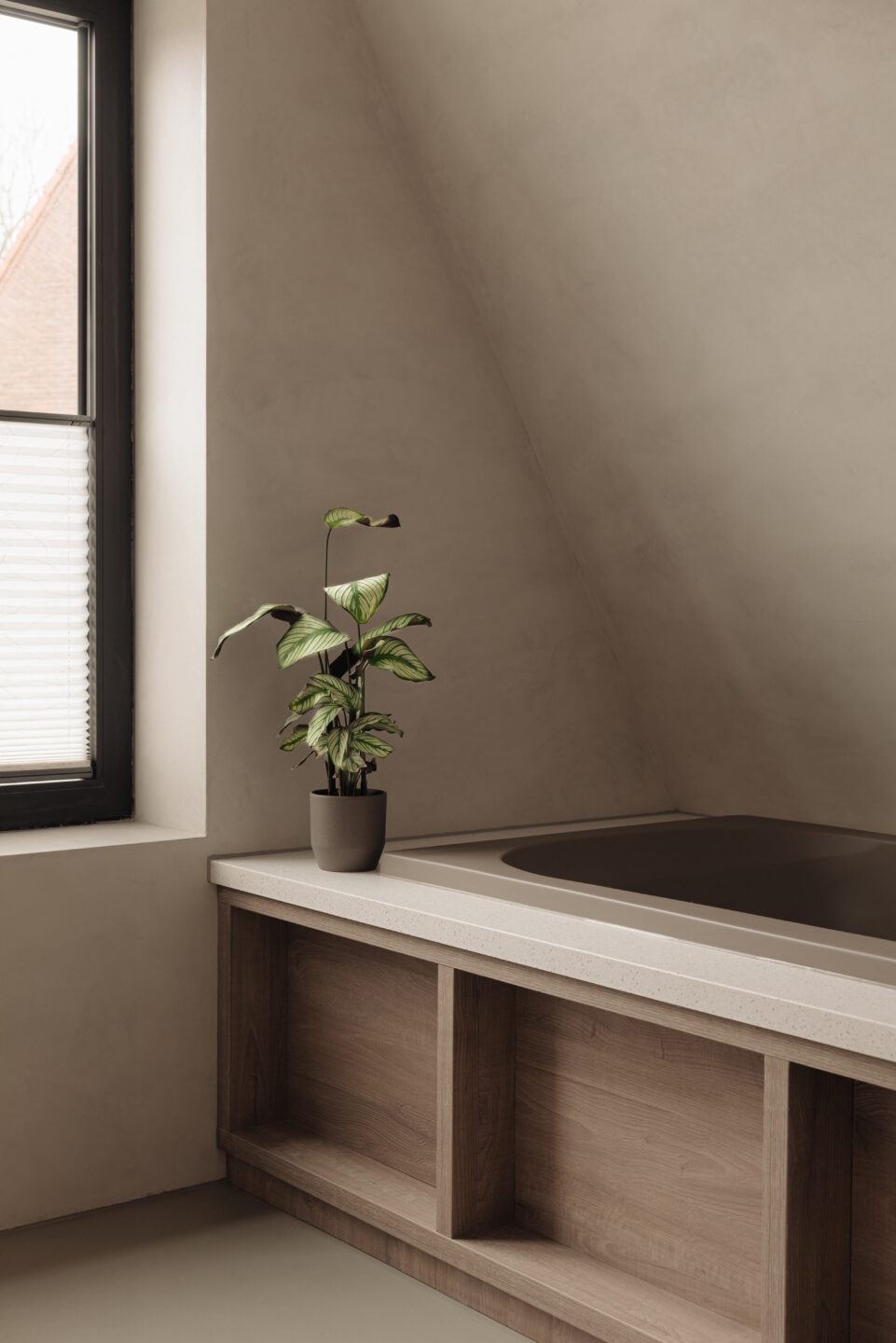 Modern ligbad gerealiseerd in plaatmateriaal met een matbruine eikenhout look (S076 Sherwood van Cleaf) en een omlijsting in solid surface decor Gadthena van Durasein